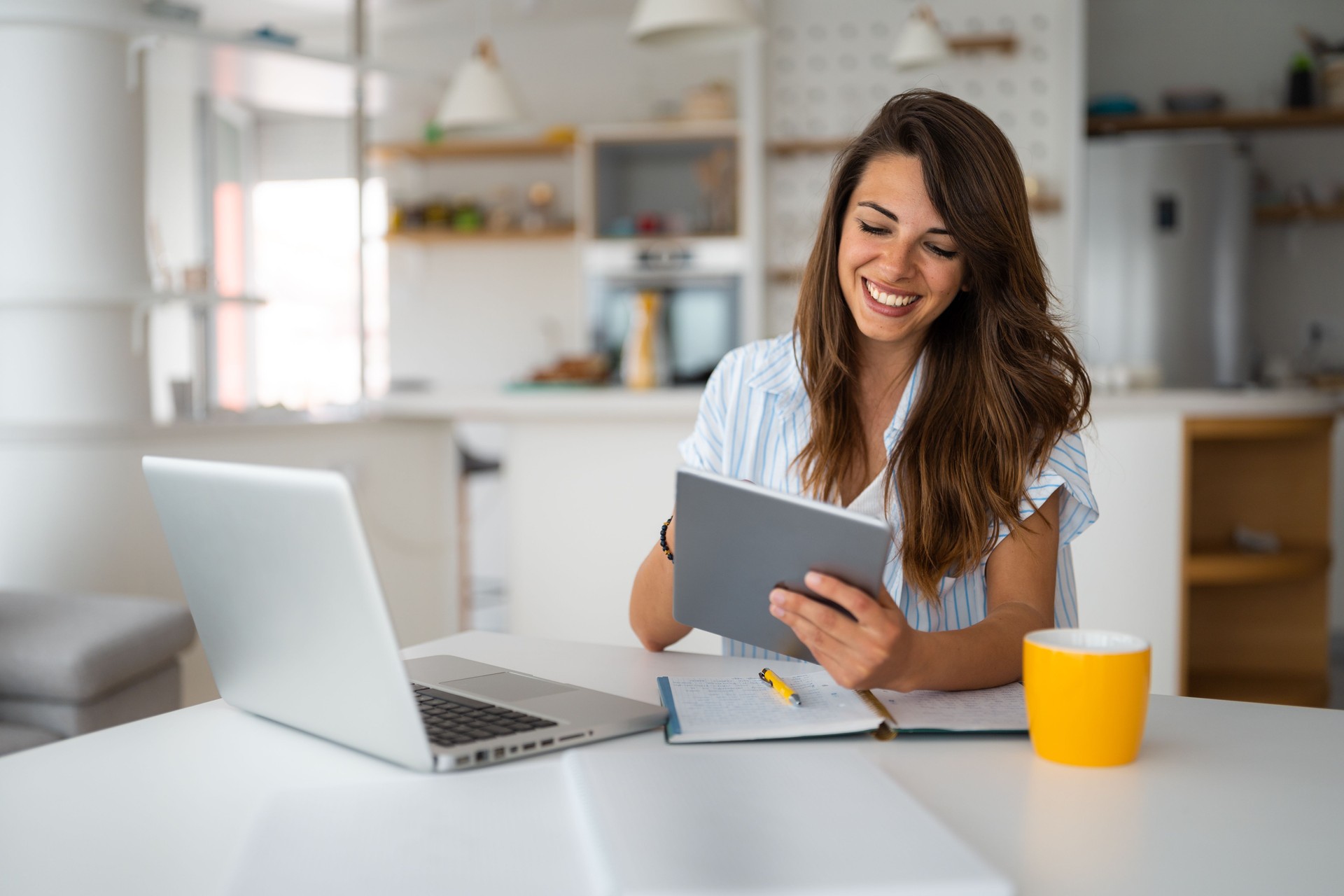 Female business person using digital tablet and laptop e-learning or remote working at home office